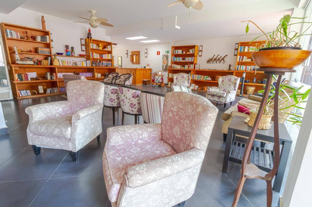 Espaço comum com biblioteca e poltronas no consultório de Patrícia Terranova